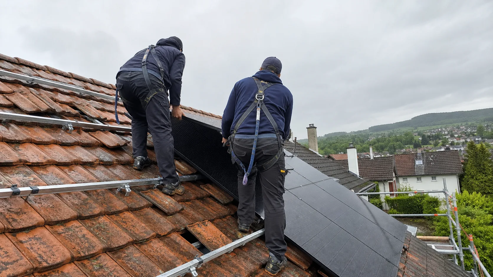 Zwei Solarteure montieren Photovoltaikmodule fachgerecht auf einem Ziegeldach